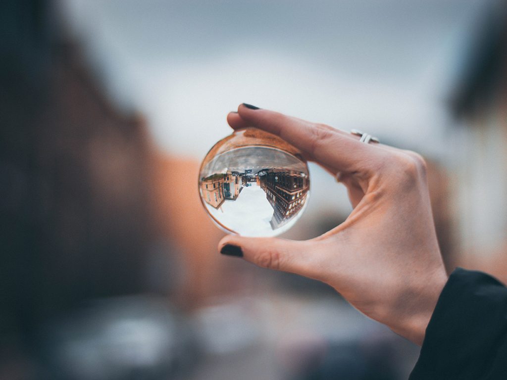 hand holding clear orb displaying a cityscape