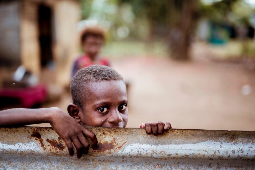 Image of a boy peering over a metal wall