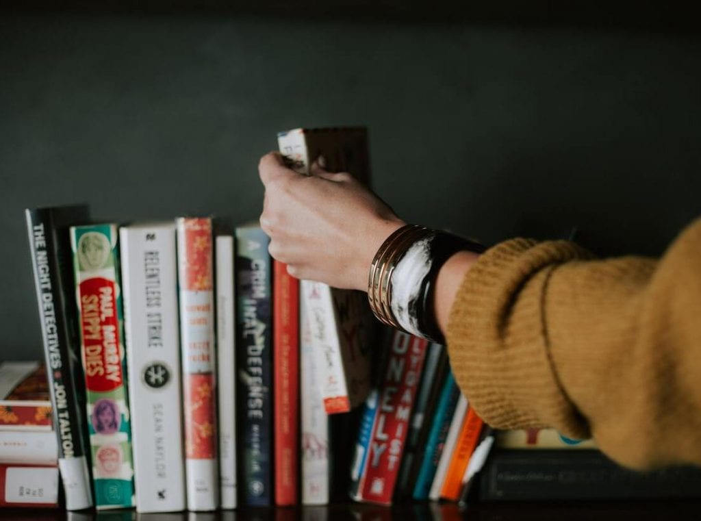line up of books and person pulling one out